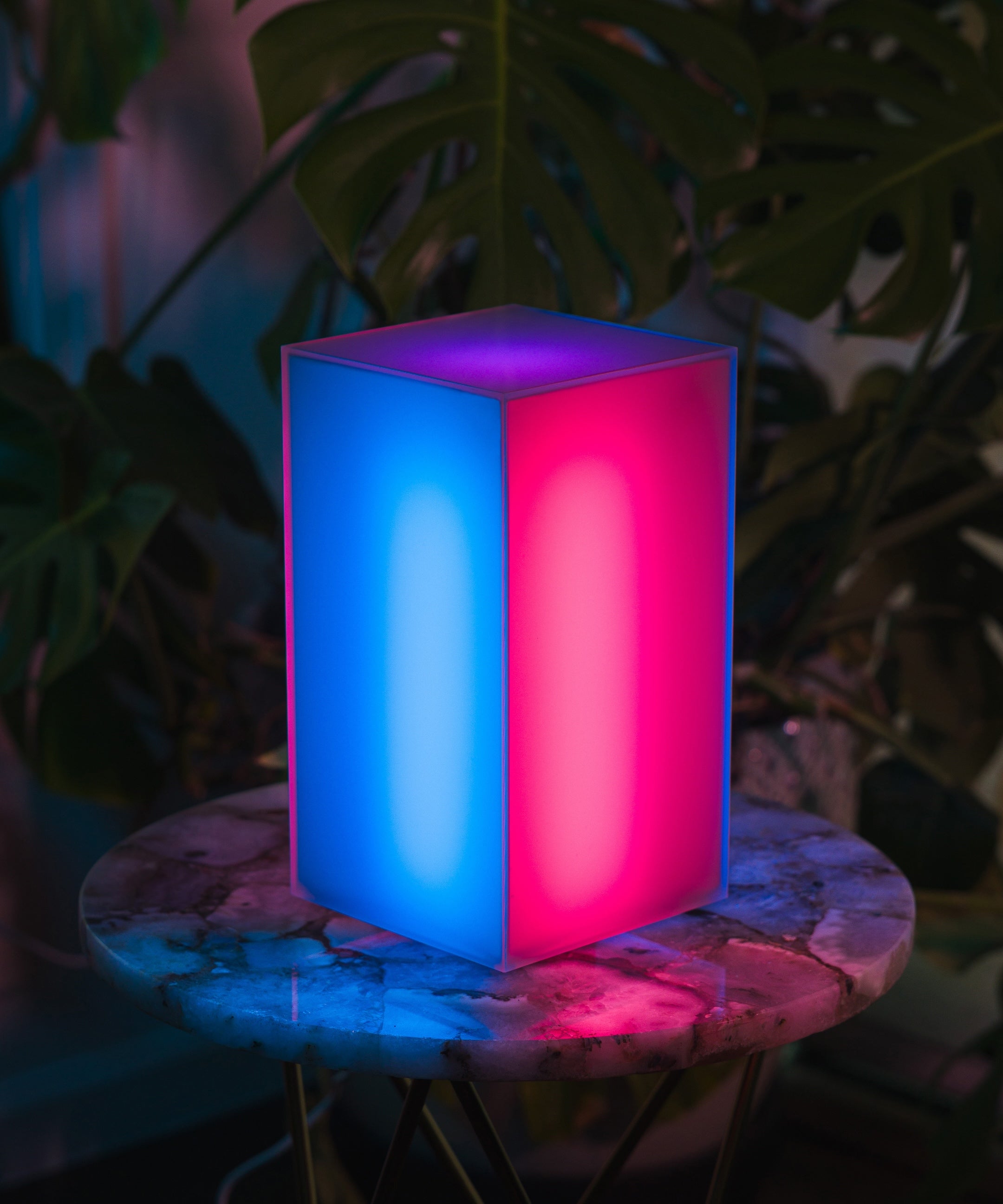 A modern designer lamp with a removable and customizable shade, radiating vibrant blue and pink colors in a dark setting. Elevated Mood Light.