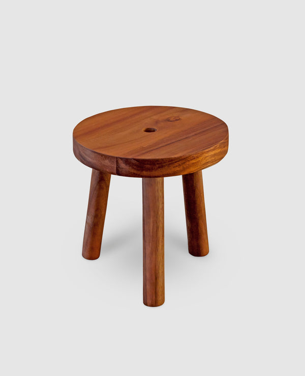 A rustic wooden stand made of acacia, featuring a circular top and three legs, with a central hole and cable clip.
